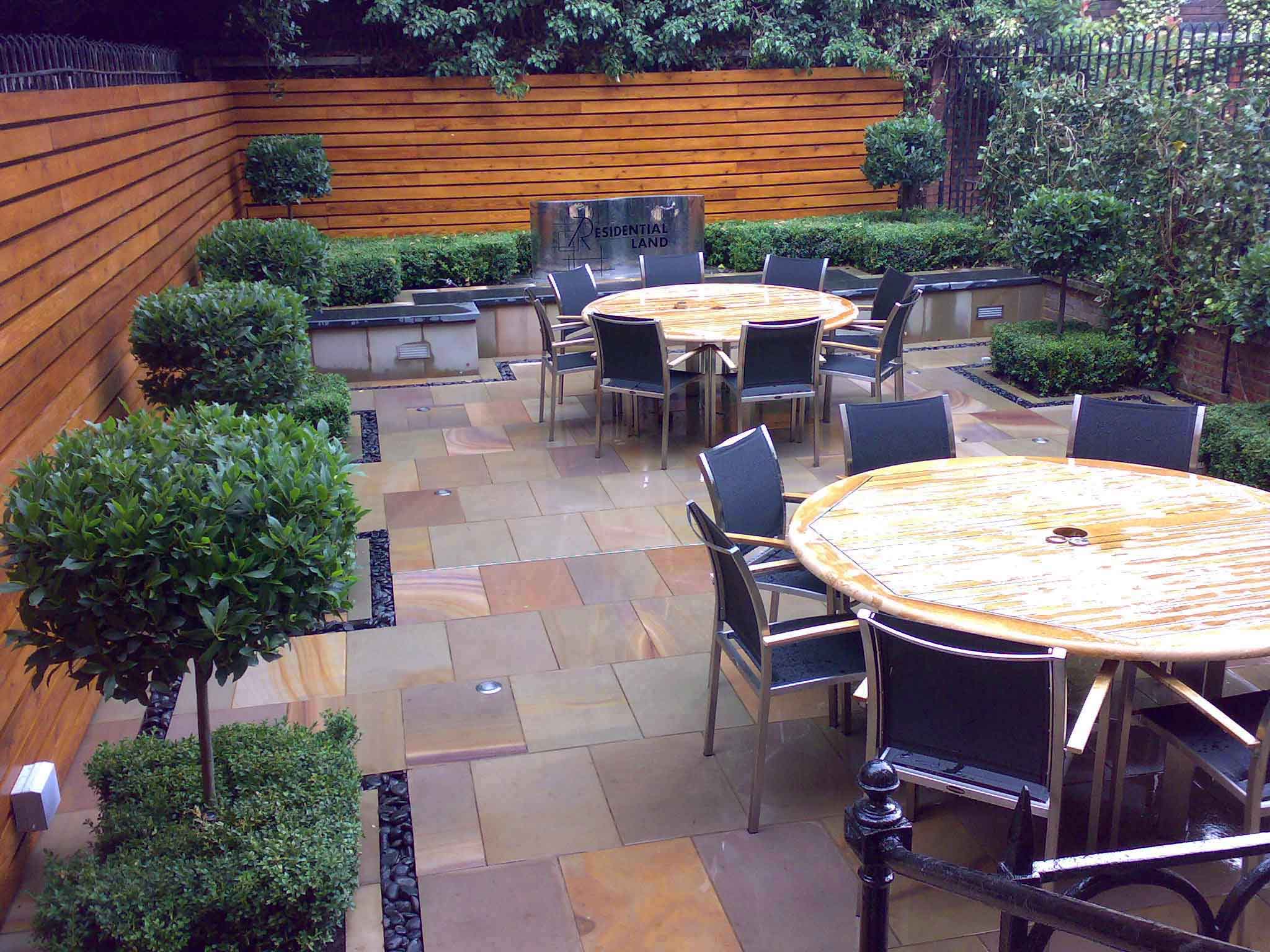Office staff garden courtyard with table chairs and modern furnishings and clipped bay trees
